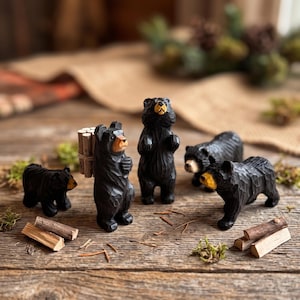 Peut inclure: Un ensemble de cinq figurines d'ours noirs sculptées dans du bois, présentant des surfaces texturées et des museaux de couleur beige. Un ours se tient debout avec un fagot de petits bois sur le dos, tandis que les autres sont dans diverses poses.