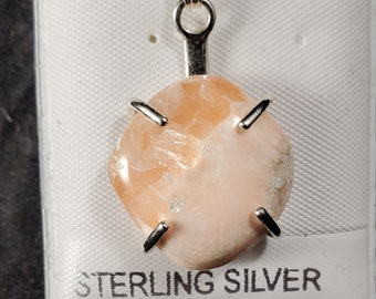 Può includere: Un ciondolo in pietra preziosa rosa e bianca con una montatura in argento sterling. Il ciondolo è esposto su uno sfondo bianco.