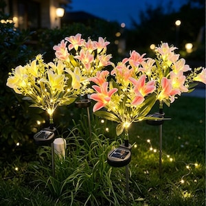 May include: A set of solar-powered garden lights shaped like lily flowers in shades of yellow and pink. Each light features a small black solar panel at the base of the stem, with thin green stalks and leaves supporting the illuminated floral heads.