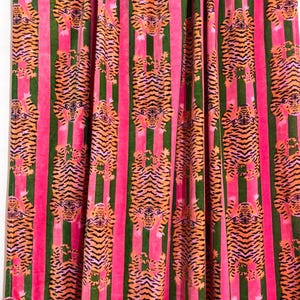 May include: A fabric curtain featuring a repeating pattern of orange and black tigers oriented vertically. The tigers are arranged in columns separated by alternating solid vertical stripes of bright pink and dark forest green velvet fabric.