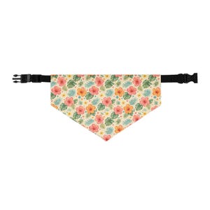 May include: A triangular pet bandana featuring a cream background with a repeating pattern of pink and orange hibiscus flowers, green monstera leaves, and blue palm fronds. The bandana is attached to a black adjustable nylon strap with a plastic buckle.