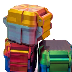 May include: Three square, multi-colored storage containers with hinged lids. The top container features a yellow and orange gradient with a starburst pattern on the lid. The lower containers display vibrant shifts of red, blue, green, and purple.