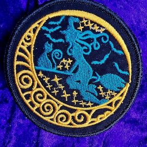 Peut inclure: Un patch brodé noir et or représentant une sorcière volant sur un balai avec deux chats noirs devant un croissant de lune. La lune est entourée d'étoiles et de chauves-souris.