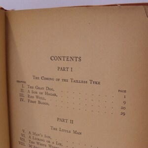 May include: A book with a brown cover and a table of contents for a novel titled "The Coming of the Tailless Tyke" and "The Little Man". The table of contents lists the chapters and page numbers.