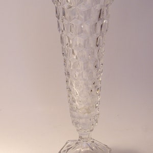 Puede incluir: Jarr&oacute;n de cristal transparente con un patr&oacute;n geom&eacute;trico texturizado. El jarr&oacute;n tiene una base hexagonal y una parte superior acampanada y dentada. El cuerpo del jarr&oacute;n es largo y esbelto.