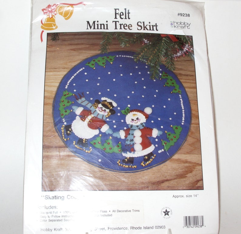 May include: A blue felt mini tree skirt kit with a snowman and Santa Claus design. The kit includes felt, floss, and decorative trims. The approximate size is 14 inches.