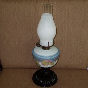 May include: A vintage oil lamp with a white frosted glass shade and a blue and white floral patterned base. The base has a black metal stand.