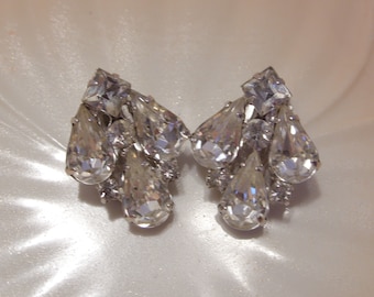 May include: A pair of silver tone dangle earrings with clear crystal teardrop shaped stones.