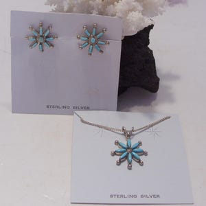 May include: Sterling silver earrings and necklace set with turquoise flower designs. The earrings are small and the necklace has a pendant.
