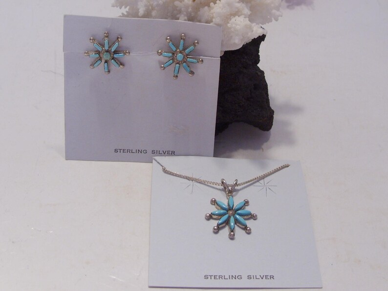 May include: Sterling silver earrings and necklace set with turquoise flower designs. The earrings are small and the necklace has a pendant.