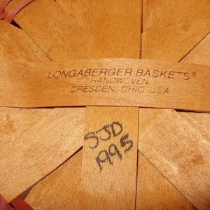 May include: Close-up of the bottom of a Longaberger basket, showing the handwoven label and the date "5/30/95" written in black ink.