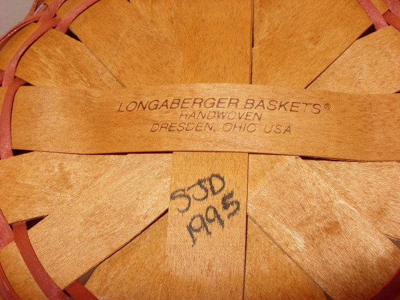 May include: Close-up of the bottom of a Longaberger basket, showing the handwoven label and the date "5/30/95" written in black ink.