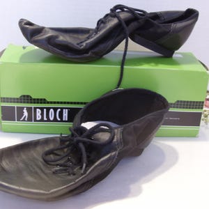 Puede incluir: Zapatos de baile de cuero negro con cordones, colocados sobre una caja verde. La caja presenta la marca "BLOCH". Estos zapatos de baile tienen una suela flexible. Los cordones est&aacute;n atados. Los zapatos son nuevos.
