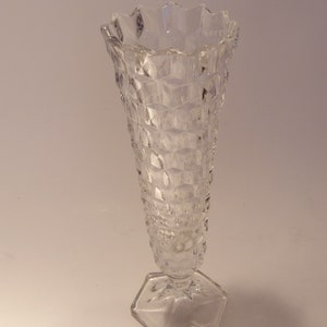 Puede incluir: Un jarr&oacute;n de vidrio transparente con base hexagonal y cuerpo texturizado con dise&ntilde;o de diamantes. El borde superior tiene un dise&ntilde;o festoneado. El jarr&oacute;n es alto y delgado, adecuado para exhibir flores o como pieza decorativa.