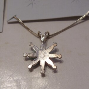 May include: Silver necklace with a star-shaped pendant. The pendant has a number "5" on the back.