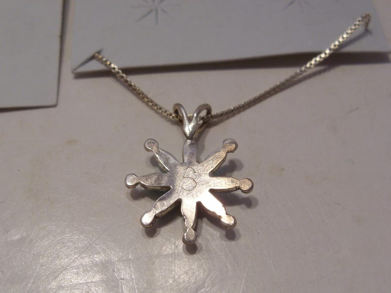 May include: Silver necklace with a star-shaped pendant. The pendant has a number "5" on the back.