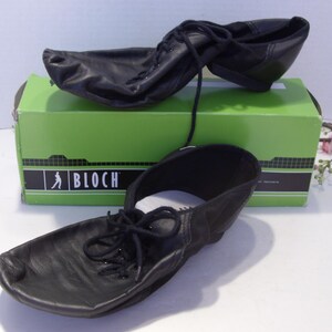 Puede incluir: Zapatos de baile de cuero negro con cordones, exhibidos en una caja verde con el logotipo de Bloch. Los zapatos est&aacute;n dise&ntilde;ados para bailar y tienen una suela suave y flexible. La caja es verde con letras negras.