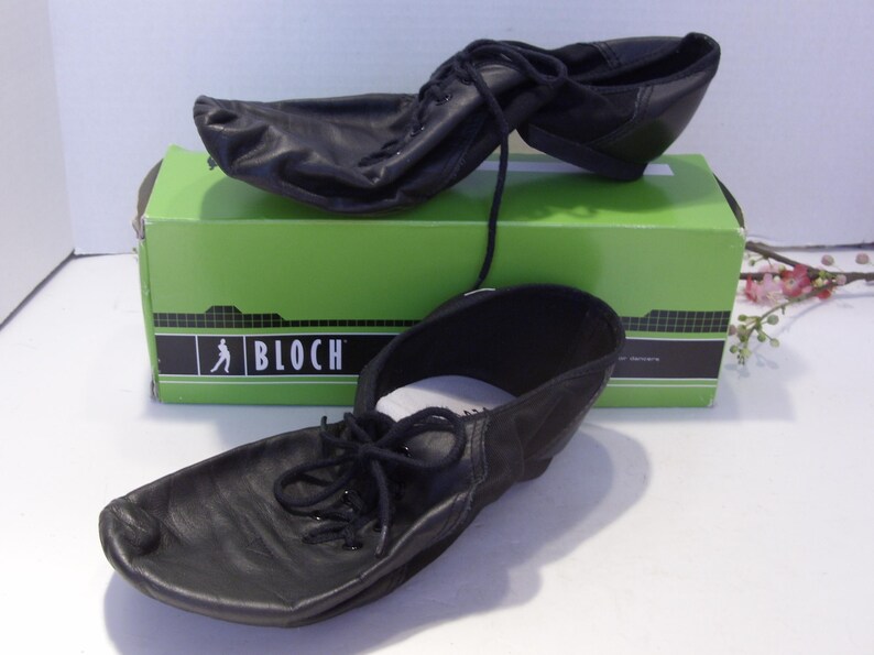 Puede incluir: Zapatos de baile de cuero negro con cordones, exhibidos en una caja verde con el logotipo de Bloch. Los zapatos est&aacute;n dise&ntilde;ados para bailar y tienen una suela suave y flexible. La caja es verde con letras negras.
