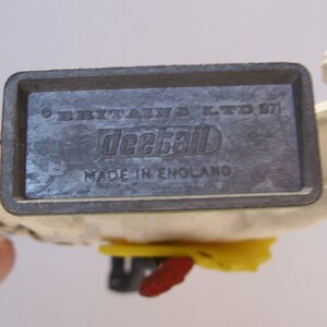 May include: A white plastic toy horse with a gray metal base. The base has the text "Britains Ltd. 1971" and "Deckal Made in England".