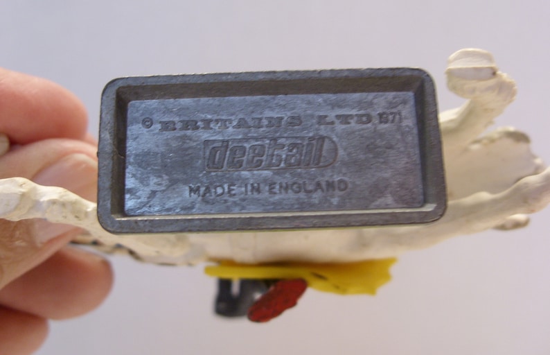 May include: A white plastic toy horse with a gray metal base. The base has the text "Britains Ltd. 1971" and "Deckal Made in England".