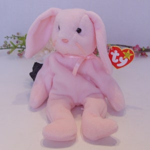 May include: Pink plush bunny with long floppy ears, a pink ribbon around its neck, and a Ty tag attached to its ear.