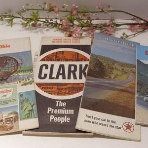 May include: A collection of vintage travel brochures and maps, including Ohio, Missouri, and Colorado. The brochures feature colorful illustrations and text, with a focus on travel and tourism. One brochure is for Clark gas stations, with the text "The Premium People."