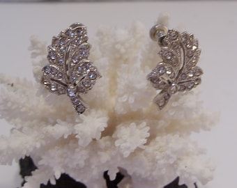 May include: A pair of silver tone earrings with a leaf design and clear rhinestones.