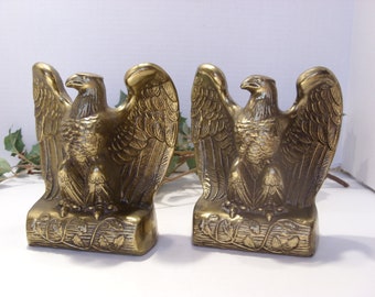 May include: A pair of brass bookends featuring a detailed eagle design. Each eagle is perched on a base with a leafy design. The bookends are a classic and elegant way to decorate a bookshelf.