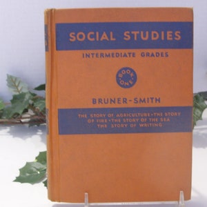 May include: A vintage book titled "Social Studies" with a tan cover and blue text. The book is labeled "Intermediate Grades" and "Book One." The author's name is Bruner-Smith. The book's cover lists the stories of agriculture, fire, the sea, and writing.
