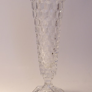 Puede incluir: Jarr&oacute;n de cristal transparente con un patr&oacute;n geom&eacute;trico texturizado. El jarr&oacute;n tiene una base hexagonal y una parte superior acampanada. El cuerpo del jarr&oacute;n es cil&iacute;ndrico, con una serie de hendiduras en forma de diamante. El jarr&oacute;n mide unos 25 cm de alto.
