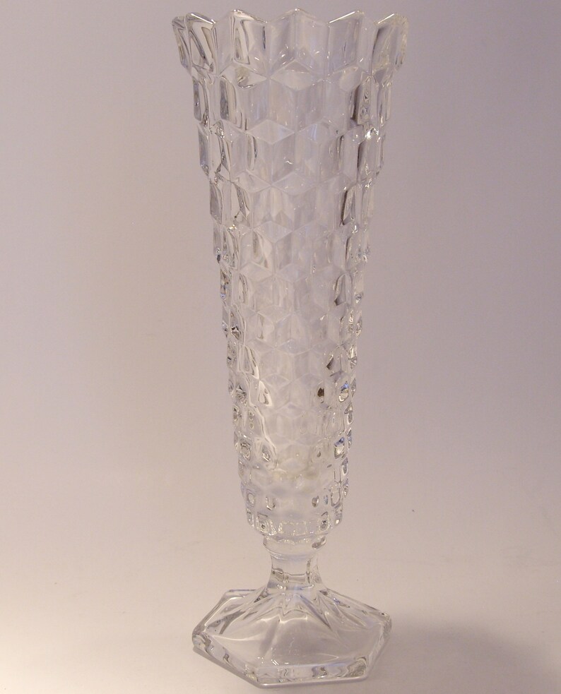Puede incluir: Jarr&oacute;n de cristal transparente con un patr&oacute;n geom&eacute;trico texturizado. El jarr&oacute;n tiene una base hexagonal y una parte superior acampanada. El cuerpo del jarr&oacute;n es cil&iacute;ndrico, con una serie de hendiduras en forma de diamante. El jarr&oacute;n mide unos 25 cm de alto.