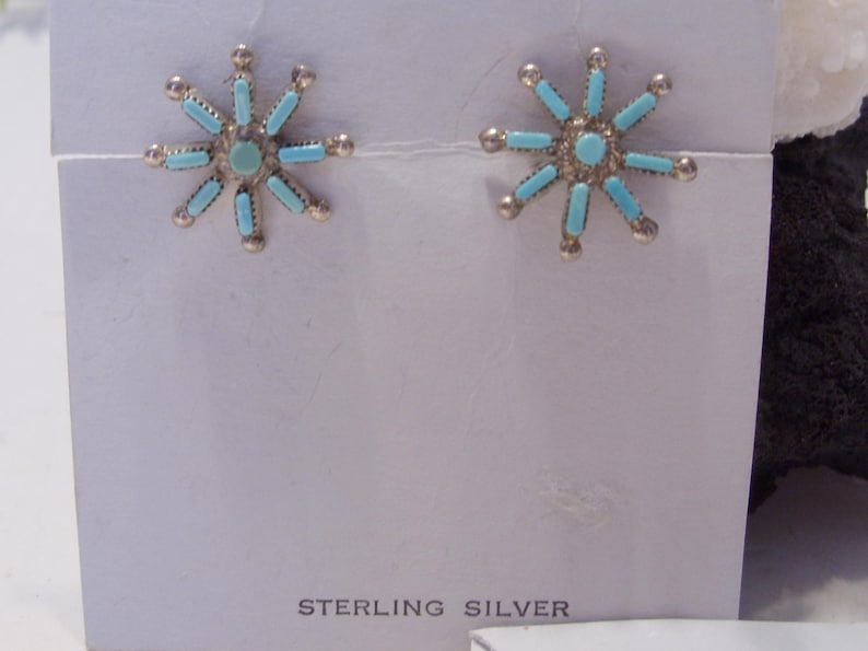 May include: A pair of sterling silver earrings with turquoise stones in a starburst design.
