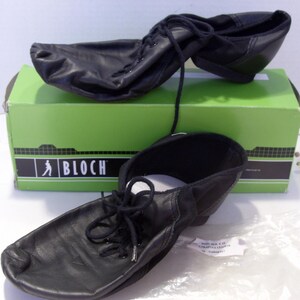 Puede incluir: Zapatos de baile de cuero negro con cordones, exhibidos frente a una caja verde con el logotipo "BLOCH". Los zapatos son nuevos y est&aacute;n dise&ntilde;ados para bailar. Una bolsa de pl&aacute;stico transparente con texto est&aacute; en primer plano.
