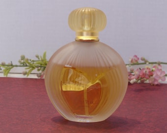 May include: A clear glass bottle of perfume with a gold cap and a textured design. The bottle is filled with a light yellow liquid.