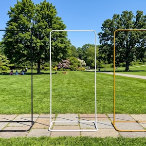 Peut inclure: Trois cadres rectangulaires en métal disposés en ligne. Les cadres sont identiques en forme et en taille, avec une structure tubulaire fine. Un cadre est noir mat, un autre est blanc et le troisième est de couleur jaune moutarde.