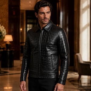 May include: A black leather jacket with a textured crocodile-skin pattern, featuring a classic collar, a full-length front zipper, and long sleeves. The jacket is constructed with a structured fit and includes two side pockets at the waist.