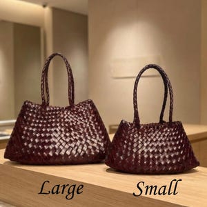 May include: Two dark burgundy woven leather handbags with braided handles. The larger bag is positioned on the left, labeled with the text Large, and the smaller bag is on the right, labeled with the text Small. Both bags feature a consistent basket-weave pattern.