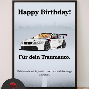 Puede incluir: Un póster enmarcado que muestra un coche de carreras blanco con alerón trasero, el texto Happy Birthday!, Für dein Traumauto., y Falls es nicht reicht, einfach noch 2.000 Geburtstage abwarten. El parabrisas muestra un gráfico de billetes de 50 y 20.