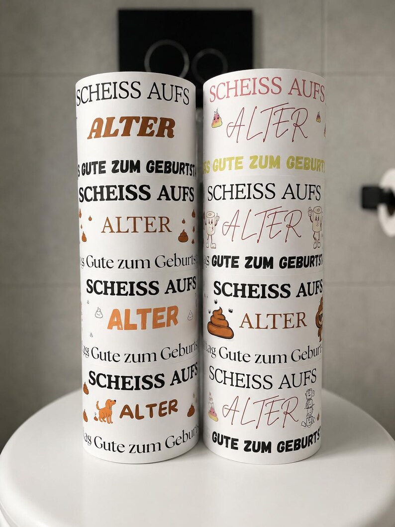 Puede incluir: Dos objetos cil&iacute;ndricos blancos con texto repetido en negro y marr&oacute;n que dice "SCHEISS AUFS ALTER" y "GUTE ZUM GEBURTSTAG". Los dise&ntilde;os incluyen peque&ntilde;as ilustraciones coloridas de personajes de caca, sombreros de fiesta y un perro marr&oacute;n.