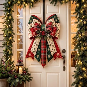 May include: A large, quilted Christmas bow decoration featuring a mix of red, green, and cream fabrics with snowflake and holly patterns. The bow is accented with a central cluster of red berries and pinecones, hanging on a white door.