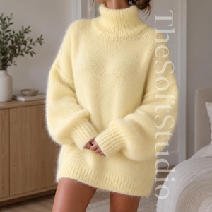 Puede incluir: Un suéter amarillo pálido de corte holgado con cuello alto, mangas largas con puños acanalados y una textura de punto grueso. El texto TheSoftStudio está orientado verticalmente a lo largo del lado derecho de la prenda en letra clara.