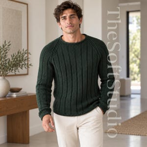 Puede incluir: Un suéter de manga larga en color verde bosque oscuro con un patrón de punto acanalado vertical, cuello redondo y mangas raglán. El suéter se combina con pantalones de color beige claro. El texto TheSoftstudio es visible a la derecha.