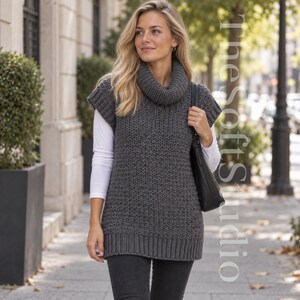 Può includere: Un gilet in maglia senza maniche color grigio scuro con un collo ad anello spesso, ampi giromanica a coste e un orlo a coste. Il capo è indossato sopra una maglia bianca a maniche lunghe con pantaloni scuri e una borsa a tracolla nera.