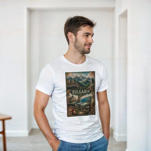 May include: A white short-sleeved t-shirt featuring a rectangular graphic print on the chest. The design displays a collage of Bulgarian landscapes, including mountains, coastal views, and traditional architecture, with the word BULGARIA centered.