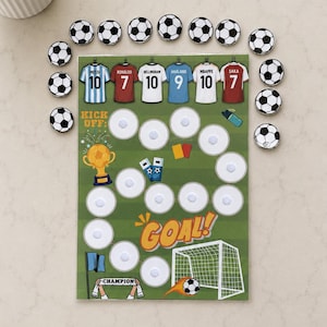 May include: A football-themed game board featuring a green pitch, a gold trophy, a goal net, and the text KICK OFF and GOAL. The board includes circular velcro spots for attaching football tokens, alongside six player jerseys with names and numbers.