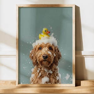 Puede incluir: Una lámina artística enmarcada que muestra a un perro de pelaje rizado color marrón dorado cubierto de burbujas de jabón blancas sobre un fondo verde salvia. Un pequeño pato de goma amarillo descansa sobre la cabeza del perro entre la espuma.