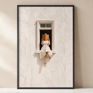 Könnte beinhalten: Ein gerahmter Kunstdruck, der eine Person in einem weißen Kleid zeigt, die in einem Fensterrahmen sitzt und ein offenes beiges Buch vor das Gesicht hält. Die umgebende Wand hat eine strukturierte, cremeweiße Putzoberfläche und der Rahmen ist schwarz.