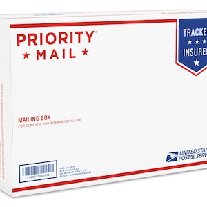 May include: White Priority Mail mailing box with red and blue accents. The box has the text "PRIORITY MAIL" and "TRACKED INSURED+" printed on it. The box is labeled "MAILING BOX FOR DOMESTIC AND INTERNATIONAL USE".