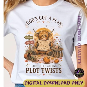 May include: A white t-shirt featuring a graphic of a fluffy highland cow holding a map. The text reads GOD'S GOT A PLAN and I JUST KEEP ADDING PLOT TWISTS. The design includes directional signs, a wooden stool, pumpkins, and autumn leaves.