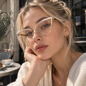 May include: Cat-eye glasses featuring a thin gold metal frame with white accents along the upper brow line. The glasses have clear lenses and adjustable nose pads, showcasing a sleek design that highlights the gold metal bridge and temple arms.